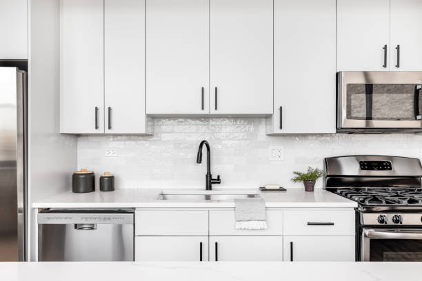 A white kitchen detail shot with a black faucet and tiled backsplash by Kitchens by RUPP